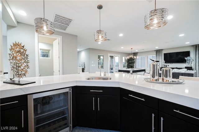 kitchen featuring decorative light fixtures, sink, and beverage cooler