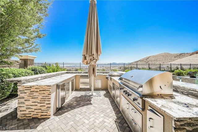 view of patio with an outdoor kitchen, area for grilling, and a mountain view