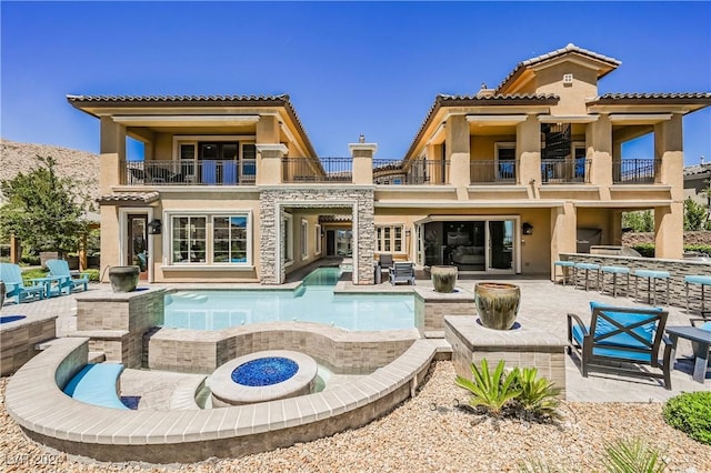 rear view of house featuring a balcony, an outdoor fire pit, and a patio area