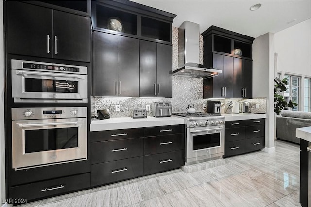 kitchen featuring decorative backsplash, wall chimney range hood, and appliances with stainless steel finishes