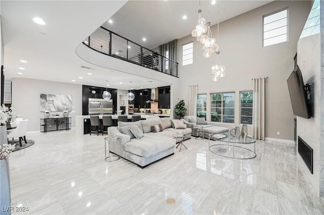 living room with a fireplace, a high ceiling, and a chandelier