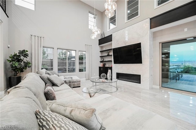 living room featuring a high ceiling, a notable chandelier, and a premium fireplace