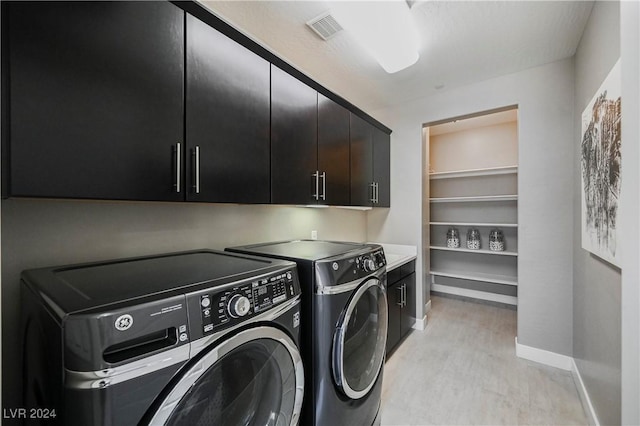 washroom with cabinets and washing machine and clothes dryer