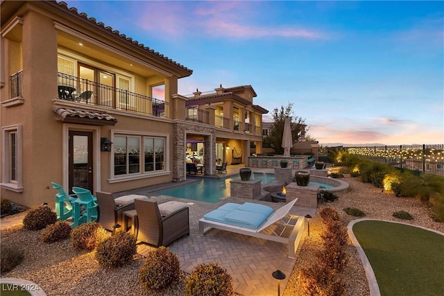 pool at dusk featuring a patio area and an in ground hot tub