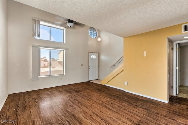 interior space featuring a towering ceiling, a textured ceiling, and hardwood / wood-style floors