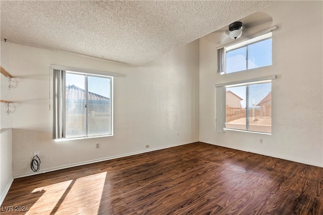 unfurnished room featuring dark wood-type flooring and a textured ceiling