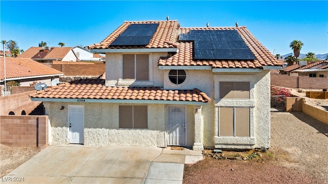 view of front of house with a patio area and solar panels