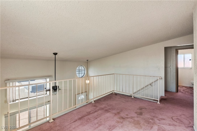 unfurnished room featuring lofted ceiling, carpet flooring, and plenty of natural light