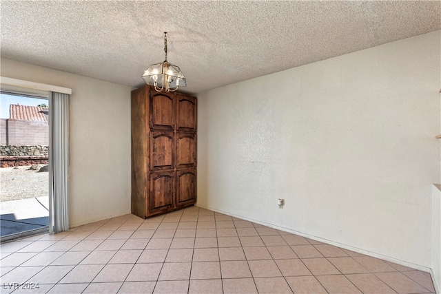 tiled spare room featuring a textured ceiling and a chandelier