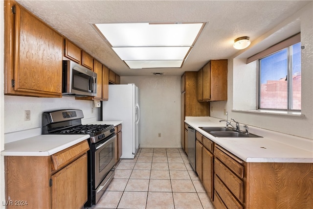 kitchen featuring sink, stainless steel appliances, a textured ceiling, and light tile patterned floors