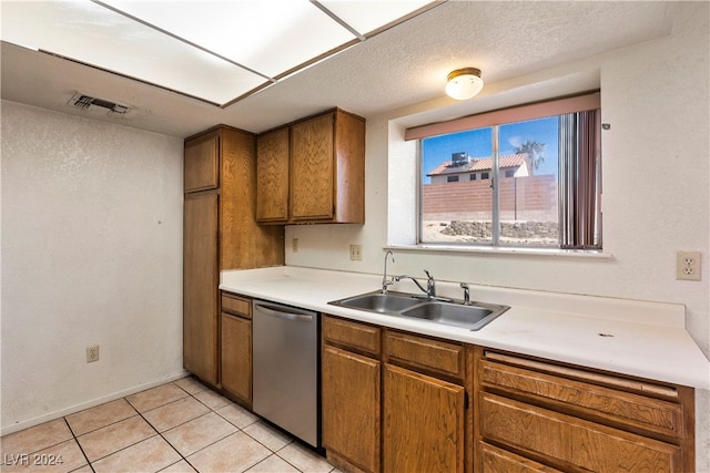 kitchen featuring sink, dishwasher, light tile patterned flooring, and a textured ceiling