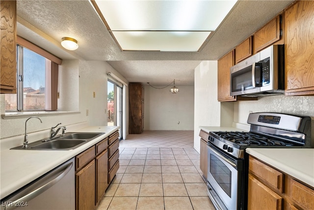 kitchen with light tile patterned floors, a textured ceiling, appliances with stainless steel finishes, and sink