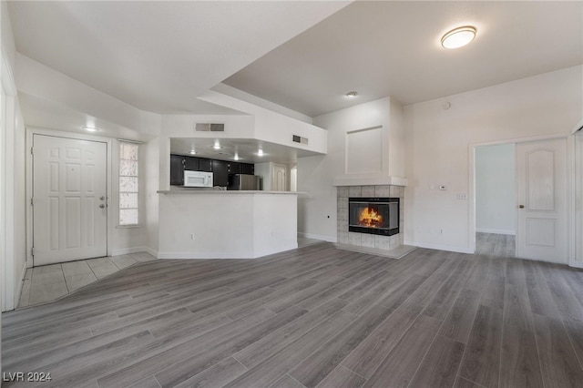 unfurnished living room with hardwood / wood-style floors and a tile fireplace