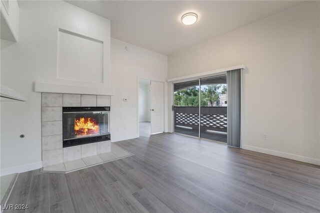 7400 W Flamingo Rd Unit 2013, Las Vegas, NV 89147 - unfurnished living room featuring a tiled fireplace, wood finished floors, and baseboards
