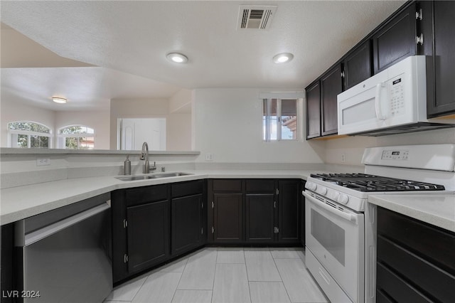 kitchen featuring white appliances, sink, and a textured ceiling