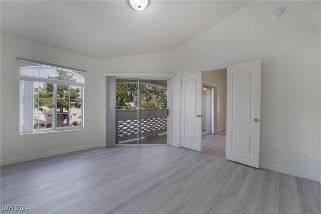 empty room with light wood-type flooring and vaulted ceiling