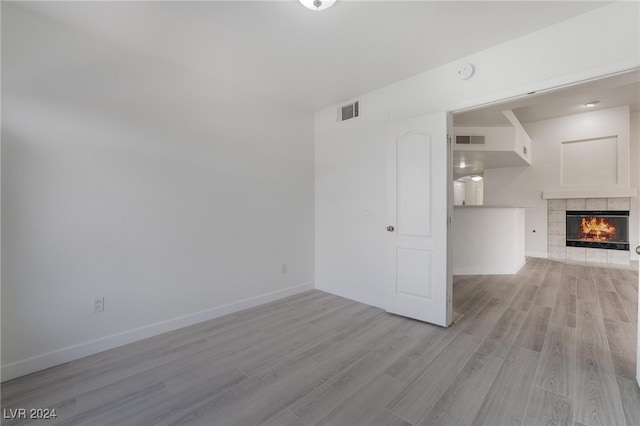 unfurnished living room with light hardwood / wood-style floors and a tiled fireplace