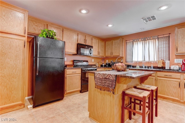 kitchen with light brown cabinets, black appliances, dark stone counters, and a kitchen island