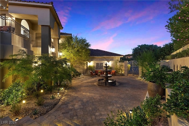 patio terrace at dusk featuring a balcony