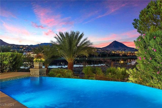 pool at dusk with a water and mountain view