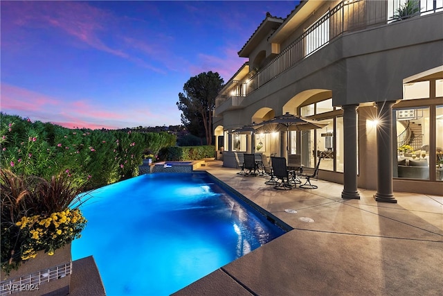 pool at dusk with a patio area