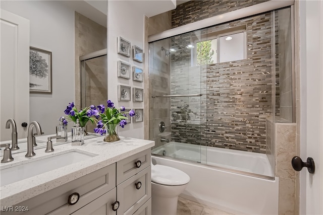 full bathroom featuring vanity, combined bath / shower with glass door, and toilet