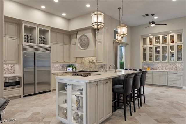 kitchen featuring decorative backsplash, hanging light fixtures, ceiling fan, appliances with stainless steel finishes, and a breakfast bar area