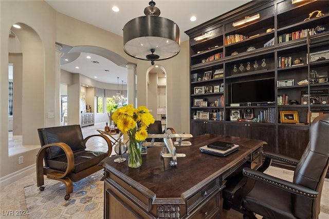 home office with a chandelier, built in shelves, and decorative columns