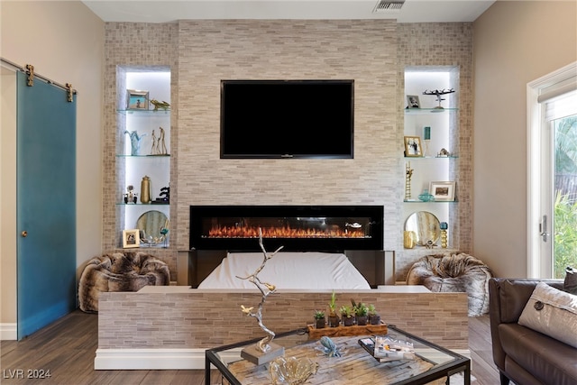 living room with a barn door, wood-type flooring, and a fireplace