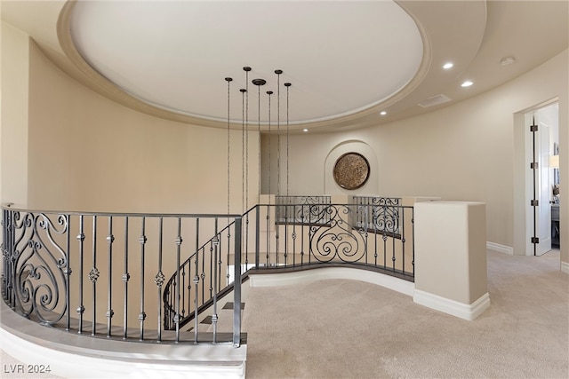 hall featuring light colored carpet and a tray ceiling