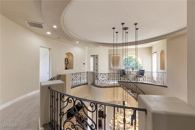 hall with light colored carpet and a raised ceiling