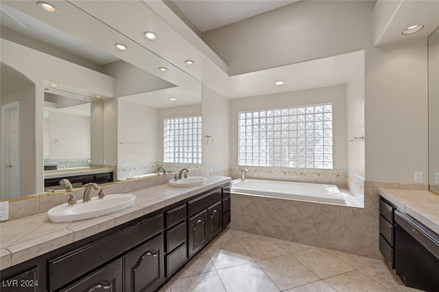 bathroom featuring tiled bath, tile patterned flooring, and vanity