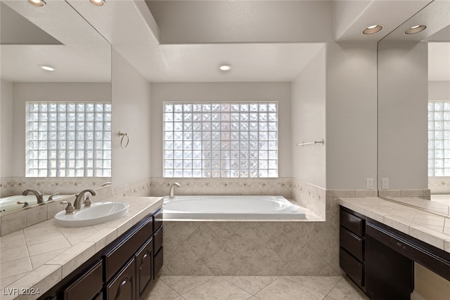 bathroom featuring vanity, tiled bath, tile patterned flooring, and a healthy amount of sunlight