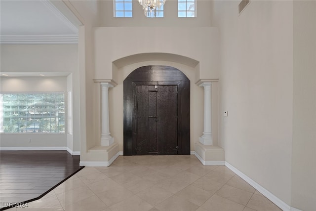 foyer entrance featuring a wealth of natural light, a notable chandelier, light hardwood / wood-style floors, and decorative columns