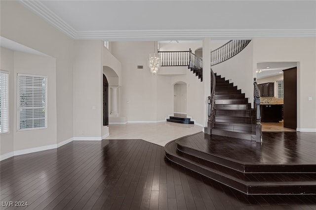 foyer entrance featuring hardwood / wood-style flooring, ornate columns, and crown molding