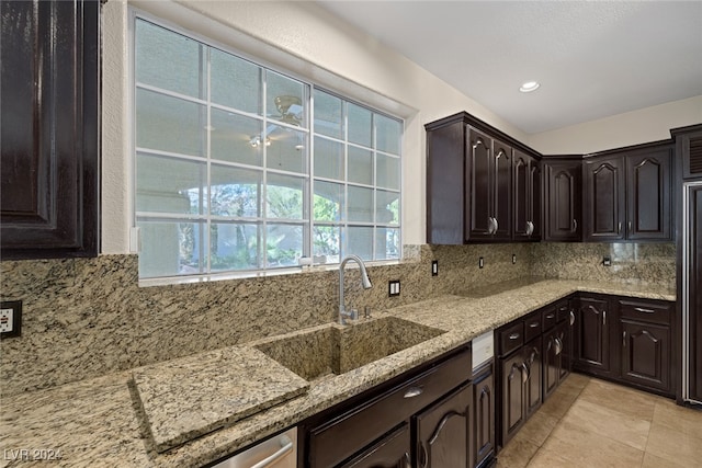 kitchen featuring light tile patterned flooring, sink, light stone counters, backsplash, and dark brown cabinets