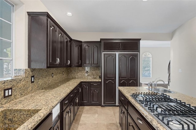 1931 Fox Canyon Cir, Las Vegas, NV 89117 - kitchen featuring stainless steel gas stovetop, light stone countertops, dark brown cabinetry, decorative backsplash, and a sink
