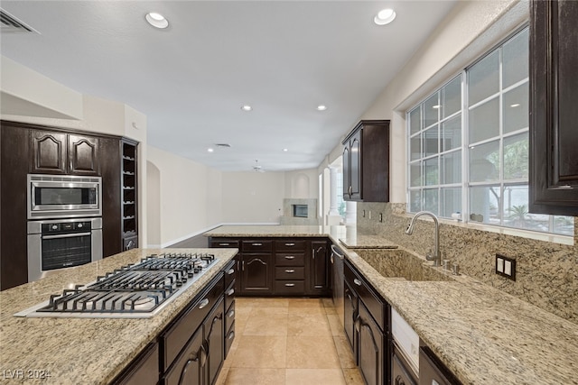 kitchen with light stone countertops, appliances with stainless steel finishes, sink, and a healthy amount of sunlight