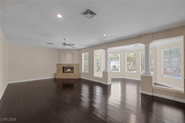 unfurnished living room featuring ornate columns, a fireplace, dark wood-type flooring, and ceiling fan