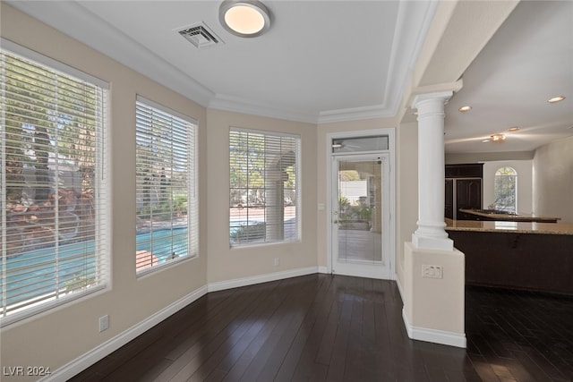 interior space featuring ornate columns, plenty of natural light, crown molding, and dark hardwood / wood-style flooring