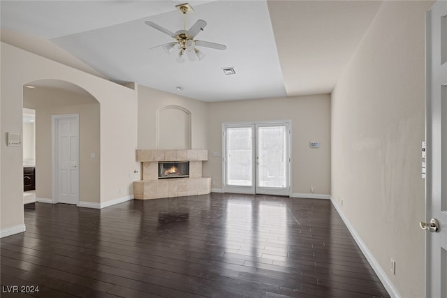 unfurnished living room featuring dark hardwood / wood-style flooring, ceiling fan, and a tile fireplace