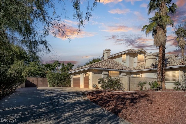1931 Fox Canyon Cir, Las Vegas, NV 89117 - mediterranean / spanish home featuring stucco siding, concrete driveway, fence, an attached garage, and a chimney