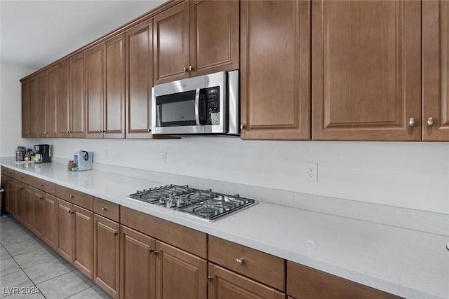 6370 Ava Ridge Ave, Las Vegas, NV 89141 - kitchen featuring appliances with stainless steel finishes, light countertops, light tile patterned floors, and brown cabinetry