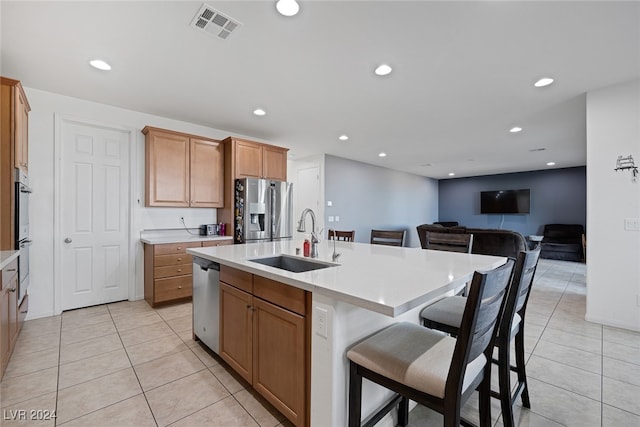 kitchen featuring appliances with stainless steel finishes, light tile patterned flooring, sink, an island with sink, and a kitchen breakfast bar