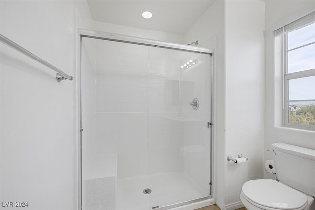 bathroom featuring a shower with shower door and toilet