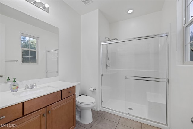 bathroom with a shower with door, vanity, toilet, and tile patterned floors