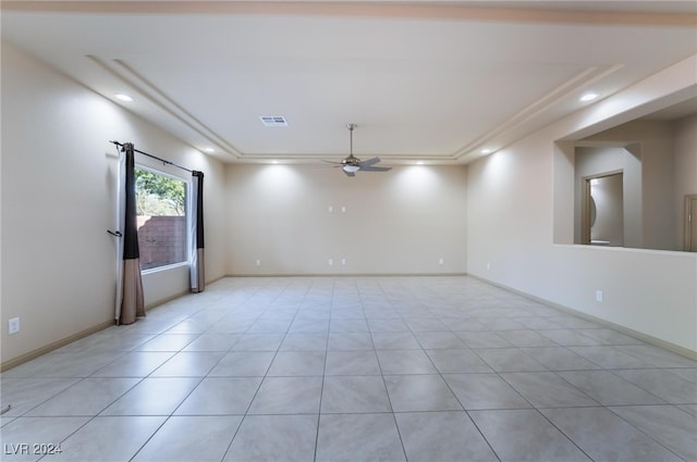 tiled spare room featuring a tray ceiling and ceiling fan