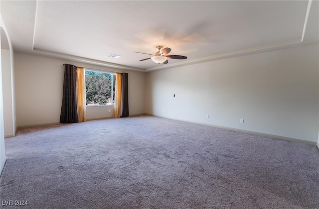 carpeted spare room featuring ceiling fan and a raised ceiling