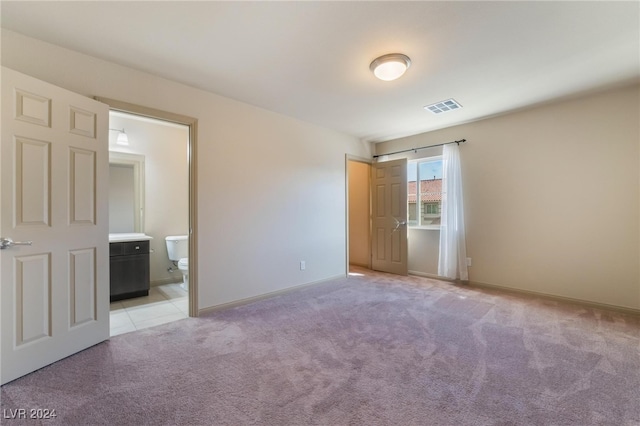 unfurnished bedroom with light colored carpet and connected bathroom