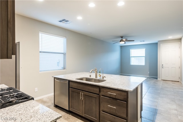 kitchen with light stone countertops, sink, appliances with stainless steel finishes, and a kitchen island with sink